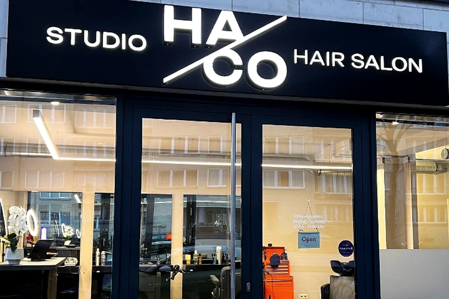 Eingang von Studio HACO am Grindelberg in Hamburg — schwarzes Studio-Schild über der Glastür